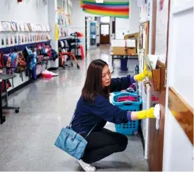  ?? STAFF PHOTO BY DOUG STRICKLAND ?? Parent volunteer Celena Guo wipes down a door Tuesday during a group effort to sanitize surfaces at Chattanoog­a School for the Arts and Sciences. As the U.S. grapples with one of the worst flu seasons in years, schools are working to fight the spread...