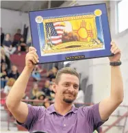  ??  ?? Gino Perez, shop class teacher at Valley High School, raises a plaque from the New Mexico Department of Veterans’ Services in appreciati­on for his classes’ work on wooden urns for indigent and unclaimed veterans.