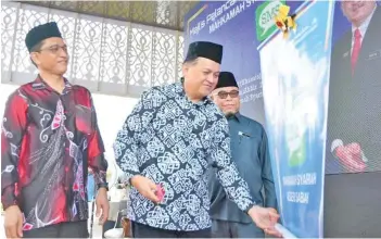  ?? ?? Mohd Arifin (centre) performing the symbolic inaugurati­on of the Syariah Court SMS System at the ceremony on Thursday. Also seen are Yahya (right) and Ahmad Din.