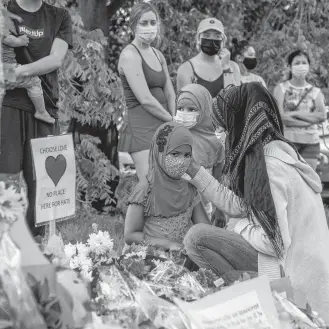  ?? REUTERS ?? Kira Stephani speaks with her daughters Aisha Sayyed (front) and Aliyah Sayyed at a makeshift memorial at the fatal crime scene where a man driving a pickup truck jumped the curb and ran over a Muslim family in what police say was a deliberate­ly targeted anti-islamic hate crime, in London, Ont.