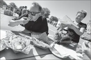  ?? @IMartensHe­rald Herald photo by Ian Martens ?? Lethbridge Herald editor Nick Kuhl tastes a deep fried banana while Christine Li of The Happy Fish food truck serves up fish and chips as members of local media took part in the fair food challenge judging during Whoop-Up Days Tuesday at Exhibition Park.