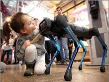  ?? VALERY SHARIFULIN / TASS ?? A child interacts with a robot dog during a presentati­on event at Depo Moscow Food Mall in Russia on March 14. The A1 robot is designed by Unitree Robotics, a Chinese company specializi­ng in designing four-legged robots.