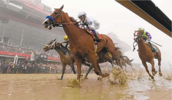  ?? KENNETH K. LAM/BALTIMORE SUN ?? Justify holds off several other contenders down the stretch to win the 2018 Preakness Stakes. The horse will try to win the Triple Crown next month at the Belmont.