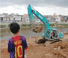  ??  ?? A child watches as an excavator cleans the Ciliwung river bank