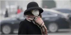  ??  ?? A woman wearing a mask walks on a road as heavy smog blankets China’s capital after the city issued its first air pollution alert for the winter season, in Beijing.