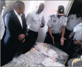  ??  ?? NO TO DRUGS: National Police Minister Fikile Mbalula, second from left, is shown the drugs and cash that were seized from a home, allegedly owned by a drug kingpin, in Phoenix.