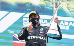  ?? PHOTO: REUTERS ?? Mercedes driver Lewis Hamilton celebrates on the podium after winning the Eifel Grand Prix at the Nuerburgri­ng in Germany, equalling Michael Schumacher’s Formula One record of 91 victories, yesterday.