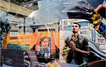  ??  ?? A man prays to the Goddess on the streets of Lucknow, with the reflection of it falling on the glass of a car parked in front