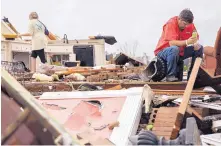  ?? BRANDEN CAMP/ASSOCIATED PRESS ?? Jeff Bullard sits in what was the foyer of his home as his daughter, Jenny Bullard, looks through the debris of the house, destroyed by a tornado Sunday. Several Georgia counties suffered severe damage.