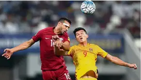  ?? — AFP ?? To no avail: China’s Xiao Zhi (right) and Qatar’s Boulem Khoukhi fighting for the ball during their World Cup Asian qualifying Group A match at the Khalifa Stadium in Doha on Tuesday.