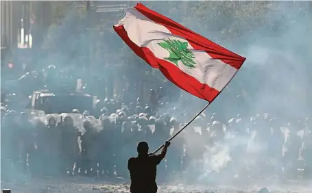  ?? FOTO REUTERS ?? S cedrem proti štítům. Jeden z demonstran­tů „ozbrojený“libanonsko­u vlajkou stojí v centru Bejrútu proti kordonu policistů.