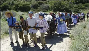  ?? PHOTO COURTESY OF ERIC BAIN ?? A group of local youths and adults push their wooden handcart during a Mormon trek reenactmen­t that took place throughout Blair Valley in Ocotillo from April 5 to April 7.