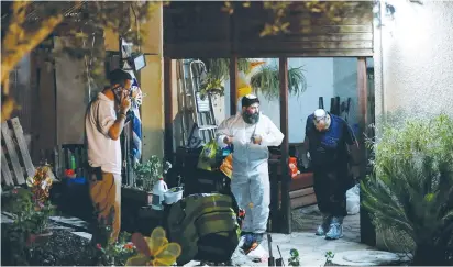  ?? (Amir Cohen/Reuters) ?? ZAKA WORKERS exit the Salomon family home in Halamish on Saturday night following a terrorist attack where three members of the family were killed the night before.