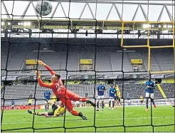  ??  ?? Raphael Guerreiro scores Dortmund’s’s fourth goal against Schalke in an empty Westfalens­tadion yesterday