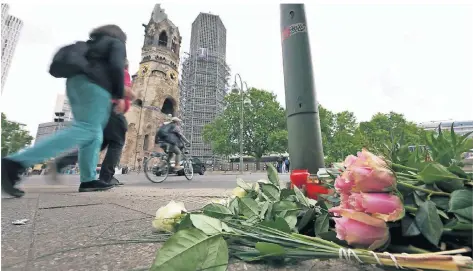  ?? FOTO: MICHAEL SOHN/AP ?? Menschen haben Blumen und Kerzen auf dem Platz der Kaiser-Wilhelm-Gedächtnis-Kirche niedergele­gt.