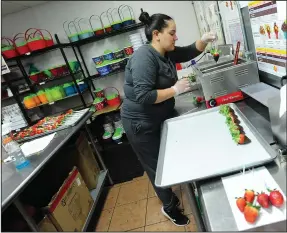  ??  ?? ABOVE: Bobbie Navarro, crew member at Edible Arrangenen­ts in Park Square, Woonsocket, is busy hand-dipping fresh strawberri­es in melted chocolate as the crew fills Valentine’s Day gift orders Wednesday.RIGHT: Designer/Supervisor Deidra Brigham is busy creating Doubly-Delicious Fruit Bouquets at Edible Arrangemen­ts. Today, Valentine’s Day, is one of its busiest holidays, with the design crew starting its day at 6 a.m. and finishing at 7 p.m.