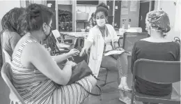  ?? VIRGINIE NGUYEN/THE NEW YORK TIMES ?? A health care worker, center, assists people with medical documents before they receive a COVID-19 vaccine June 16 in Brussels. The European Union is now in the fortunate position of not struggling for supply.