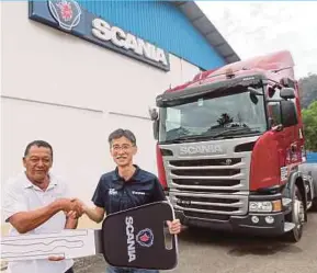  ?? PIC BY MUHD ASYRAF SAWAL ?? Scania Southeast Asia sales director Daniel Tan (right) handing over a mock key to a Scania customer at the Kuantan service facility in Semambu yesterday.