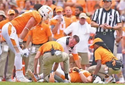  ?? STAFF PHOTO BY C.B. SCHMELTER ?? Tennessee football coach Butch Jones, center, checks on injured tight end Eli Wolf during a home game against Indiana State in September. BELOW: Darrell Taylor played with his injured right hand in a cast during the game against Indiana State.