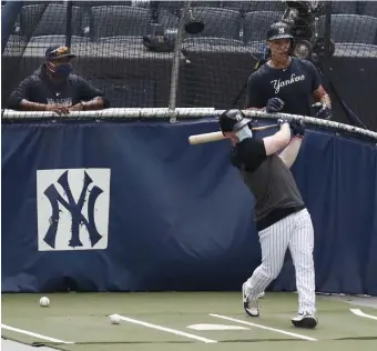  ??  ?? MASKED IN THE CAGE: Yankees hitting coach Marcus Thames (left) and Aaron Judge watch a masked Clint Frazier take batting practice last week.
