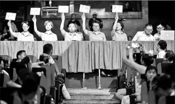  ??  ?? The jury displaying the result for a group at the final round of a city-wide square dance competitio­n at a local theatre in Shanghai.