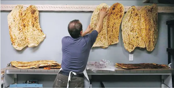  ?? PHOTOS: JIM WELLS ?? Salah Shamami hangs homemade Kurdish bread to cool at Saman Restaurant and Sangak Bakery. The traditiona­l flatbread, called sangak, is made by hand daily.