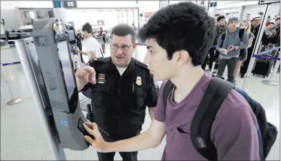  ?? David J. Phillip ?? The Associated Press U.S. Customs and Border Protection supervisor Erik Gordon helps passenger Ronan Pabhye navigate a new facial recognitio­n kiosk Wednesday at a United Airlines gate before Pabhye’s flight to Tokyo at George Bush Interconti­nental...