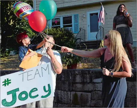  ?? SARAH GORDON/THE DAY ?? Joey Gomez, 3, reaches for balloons with his dad, Mark, and mom, Kristen, during a surprise parade Tuesday outside his home in Mystic. Joey, who has been on dialysis, recently came home after a kidney transplant.