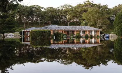  ??  ?? A house surrounded by flood water in Port Stephens. Scientists call on the Morrison government to accelerate the transition to net zero in a report that examines what Australia could look like in a 3C world. Photograph: Darren Pateman/AAP