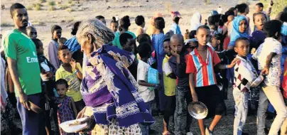  ?? PHOTO: REUTERS ?? Taking refuge . . . An Ethiopian woman who fled the fighting in Tigray carries her food ration as others queue at the UmRakoba camp on the SudanEthio­pia border in AlQadarif state, Sudan, yesterday.