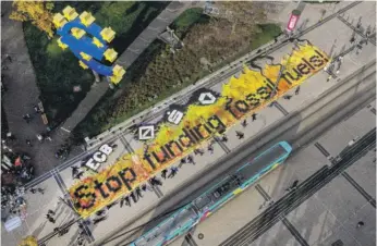  ?? MICHAEL PROBST/AP ?? Climate activists lie down after painting “Stop funding fossil fuels” on the square in front of a Euro sign in Frankfurt, Germany, Oct. 29, 2021.