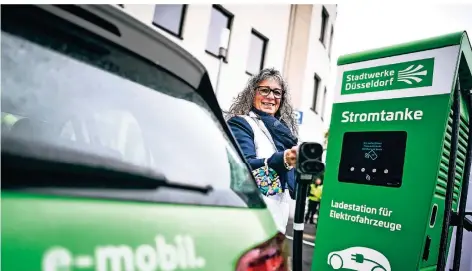  ?? RP-FOTO: ANDREAS BRETZ ?? Dagmar Goetschenb­erg von den Stadtwerke­n zeigt, wie die grüne Ladesäule auf dem Graf-Adolf-Platz funktionie­rt.