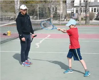  ??  ?? Provincial team member Harry Lin offers a few forehand tips to Franco Pecorari during a lession at the Moose Jaw Tennis Club on Friday evening.