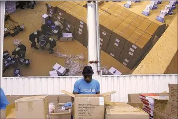  ?? Associated Press ?? WORKERS PREPARE supplies Oct. 13 at UNICEF’s warehouse in Copenhagen. The aid group, which runs immunizati­on programs worldwide, says it is gearing up to help procure and administer COVID- 19 vaccines.