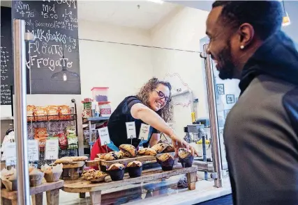  ?? [PHOTO BY AMANDA VOISARD FOR THE WASHINGTON POST] ?? Faith Holmes laughs with regular customer Kareem Copper on Jan. 6. She began her business to fulfill her dream of combining her passions - baking and civic action.