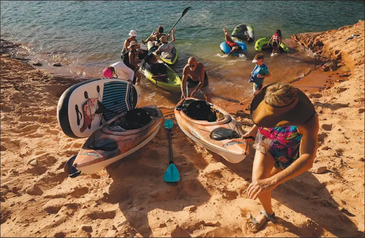  ?? BRITTANY PETERSON / ASSOCIATED PRESS ?? Tourists carry a kayak up a sandy hill in June 2022 in Page, Ariz. John Weisheit, a longtime river guide who has spent much of his 68 years in and around the Colorado River and its lakes has long believed the water system wasn’t sustainabl­e for the population­s it’s intended to support. “We need to respect the river for what it is, and we’re not doing that,” he says.