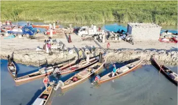  ??  ?? An aerial view of fishermen by their moored boats in the Chibayesh marshland in Iraq’s southern Ahwar area.