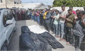  ?? ?? Des personnes en deuil prient devant les corps des Palestinie­ns tués lors d’une frappe israélienn­e à Nuseirat, dans la bande de Gaza. - Associated Press: Abdel Kareem Hana