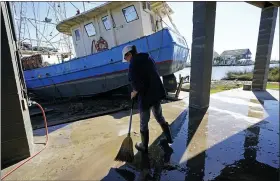  ??  ?? Ray Garcia sweeps water from her home after a boat washed up against it in Lakeshore, Miss., on Thursday. Hurricane Zeta passed through Wednesday with a tidal surge that caused the boat to become unmoored. GERALD HERBERT — THE ASSOCIATED PRESS
