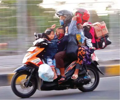  ?? AHMAD KHUSAINI/JAWA POS ?? ABAIKAN PROTOKOL KESEHATAN: Pengendara sepeda motor yang melintas di Suramadu membonceng­kan anak dan istrinya.