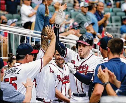  ?? CURTIS COMPTON / CCOMPTON@AJC.COM ?? Braves first baseman Freddie Freeman gets high fives in the dugout after hitting a solo home run for a 2-0 lead over the Mets in the eighth inning Wednesday, but it was an RBI single earlier in the game that set the table for the win.