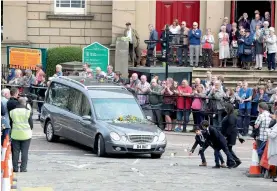  ?? — AP ?? Mourners throw roses as the hearse carrying the coffin of MP Jo Cox passes in Batley, England, ahead of her private funeral service on Friday. The mother of two young children died on June 16 after she was attacked outside a library in Birstall, England.