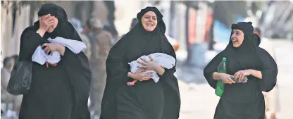  ??  ?? Left: Women carry their babies as they celebrate the end of Isil occupation of the Syrian city.
