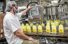  ?? Michael M. Santiago/Post-Gazette ?? JT Bendel, a machine operator at Turner Dairy Farms in Penn Hills, works a machine as half-gallon lemonades on a conveyor belt make their way to be packaged on March 5.