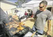  ??  ?? Volunteers Doug Bradshaw (left) and John Dion, with Mission U-Too, a local ministry, prepare food for evacuees and first responders behind the Smithville Recreation Center on Sunday morning.