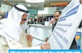  ?? — KUNA ?? KUWAIT: Deputy Foreign Minister Khaled Al-Jarallah signs an anti-human traffickin­g campaign poster yesterday.