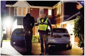  ??  ?? Dawn arrest: An officer leads a suspect away in handcuffs