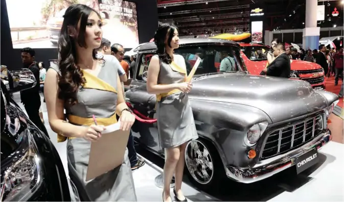  ?? — AFP ?? JAKARTA: Models pose with Chevrolet cars on display at the Indonesia Internatio­nal Motor Show in Jakarta yesterday. Indonesia has forecast vehicle sales in 2017 to reach 1.1 million units, growing at a rate of five percent, as Indonesia’s economy is...