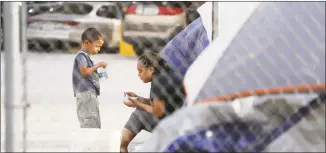  ?? Eric Gay / Associated Press ?? Suanny Gomez, 24, from Honduras, who is seeking asylum in the United States, waits in a tent with her 5-year-old son, William, on Tuesday in Matamoros, Mexico. Gomez said she does not have money to pay a proposed fee for seeking asylum.