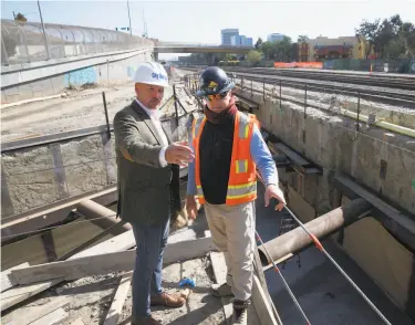  ?? Photos by Paul Chinn / The Chronicle ?? Mike Futrell (left), South San Francisco city manager, discusses the Caltrain station under constructi­on with Joe Gilmartin. A developer hopes to break ground on a biotech complex next to the station.